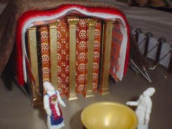 Photo of parially painted priest figures in front of completed temple front